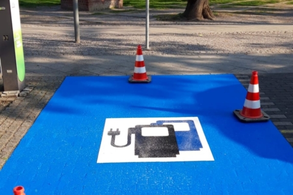 Bild: Der E-Lade-Parkplatz hat eine leuchtend blaue Grundierung sowie ein Symbol erhalten, das eindeutig auf einen Ladevorgang hinweist