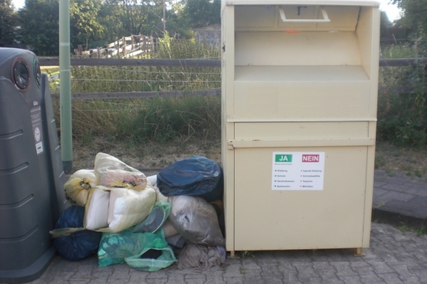 Bild: SÃ¤cke mit Altkleidern neben dem Container.