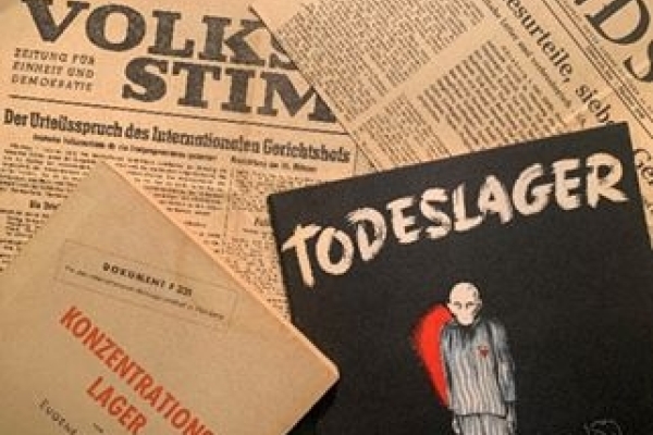 Bild: Im Hintergrund sind Abbildungen mehrerer alter Zeitungen. Links im Vordergrund liegt ein Heft auf dem steht 