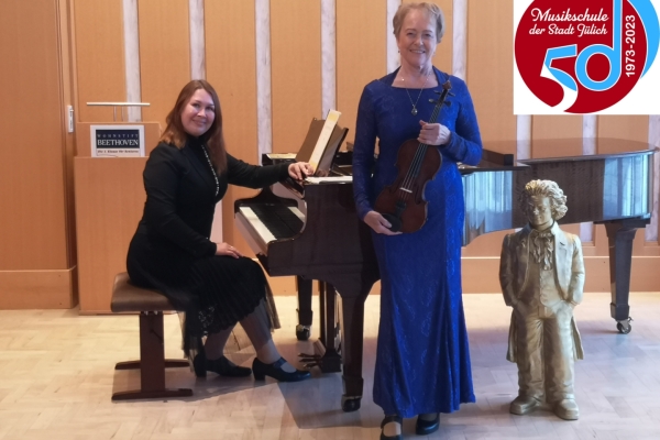Neujahrskonzert Bild: Eien Frau sitzt am Klavier, davor steht eine weitere Frau mit einer Geige.