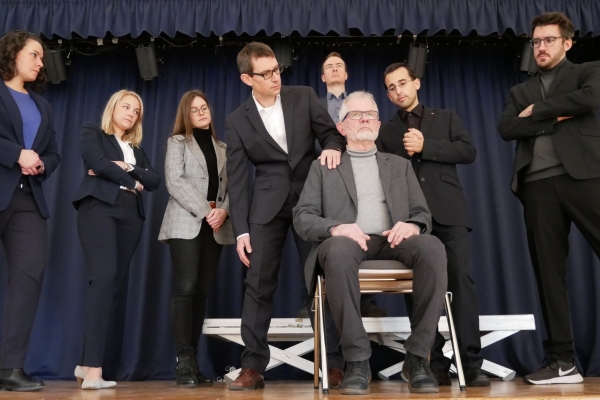 Theater: Gott Bild: Das gesamte Ensemble steht hinter Richard Gärtner (sitzend auf einem Stuhl in der Mitte)