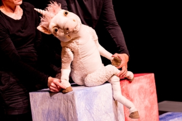 Ich bin Einhorn - wer bist du? Bild: Das Einhorn (Puppe) sitzt auf einer Kiste.