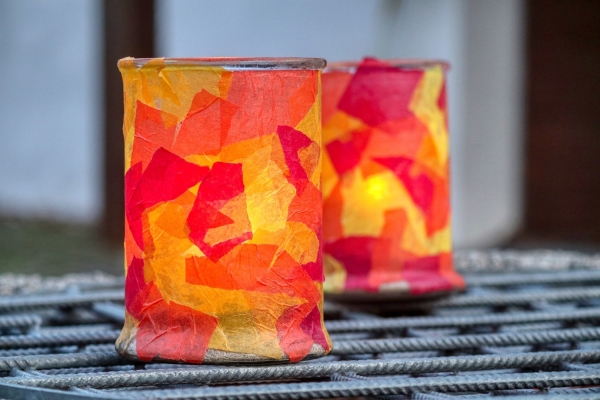 Bild: Zwei gebastelte und mit roten und gelben Papierstücken beklebte Laternen.
