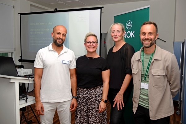vier Personen stehen vor einer Leinwand