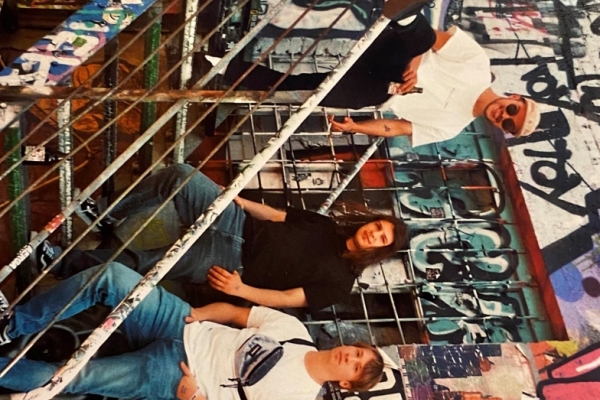 Bild: Die drei Musiker der Band Capiluns auf einer Treppe vor einer mit Graffittis besprühten Wand