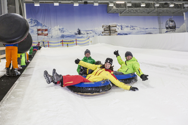 Schneerodelbahn Bild: 3 Erwachsene rodeln in Reifen eien Piste hinunter