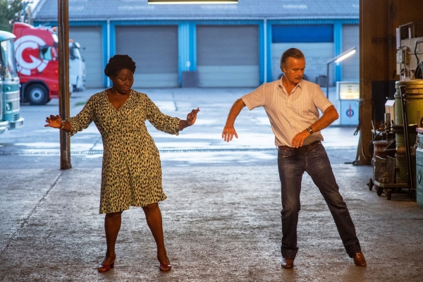 Filmfrühstück: Die Rumba Therapie Bild: Eine Frau und ein Mann tanzen in einer Halle. Das Tor ist offen und man sieht links das Voderteil eines Busses.