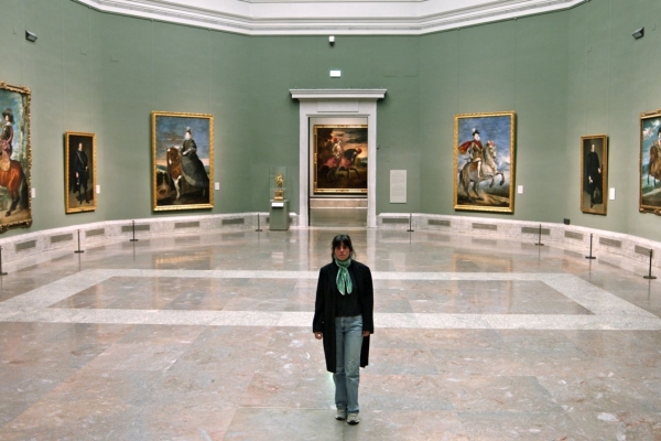 Bild: Eine Frau geht in einem runden Saal, an dessen Wänden Bilder hängen.