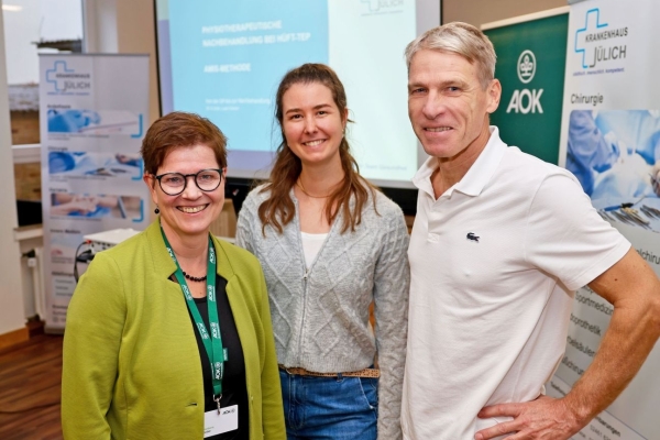 Zwei Frauen und ein Mann stehen vor einer Leinwand