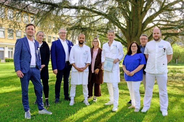 6 Männer und 3 Frauen stehen im Garten des Krankenhauses