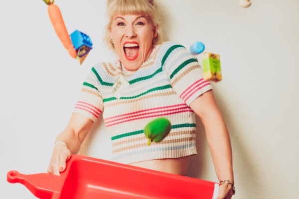 Bild: Marie Lumpp hat einen Spielzeuganhänger in den Händen und Spielzeuge wirbeln um sie herum.