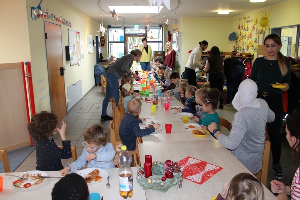 Eltern kochen ein internationales Weihnachtsdinner Bild: Kinder, Eltern und Personal genießen das Essen