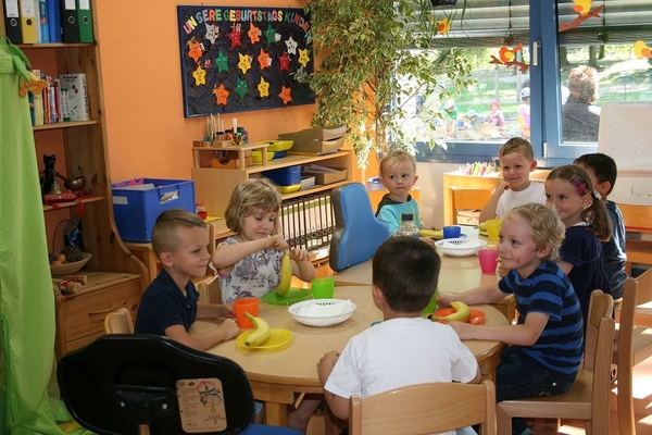 Bild: Mehrere Kinder sitzen um einen Tisch und essen gemeinsam.