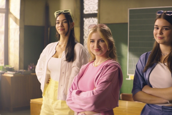 Bild: Drei Mädchen stehen in einem Klassenraum.