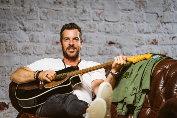 Konzert: Torben Klein Bild: Torben Klein mit Gitarre auf einem Sofa