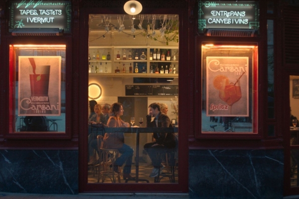 Bild: Eine Frau und ein Mann sitzen sich in einem Lokal an einem Tisch gegenüber. Das Bild wurde nachts von draußen aufgenommen.